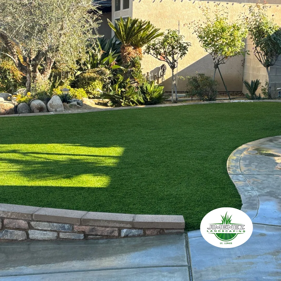 Lush artificial turf lawn installation by Jimenez Landscaping, surrounded by decorative rocks and various plants, enhancing the landscape in Bakersfield.