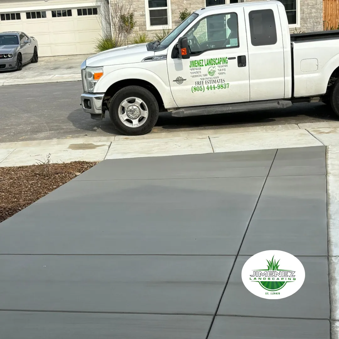 Concrete driveway installation by Jimenez Landscaping in Bakersfield, showcasing a smooth, polished surface with a landscaping truck parked nearby.