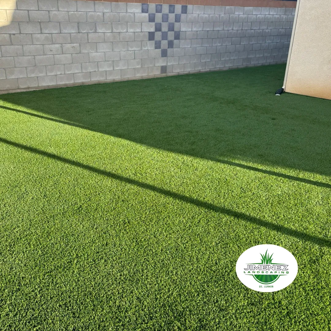 Artificial turf installation showcasing vibrant green lawn in Bakersfield, with decorative block wall in the background, emphasizing quality landscaping by Jimenez Landscaping.