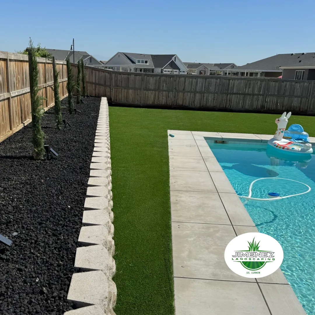 Backyard landscape featuring artificial turf, decorative rock, and a swimming pool with a floating toy, designed by Jimenez Landscaping in Bakersfield.