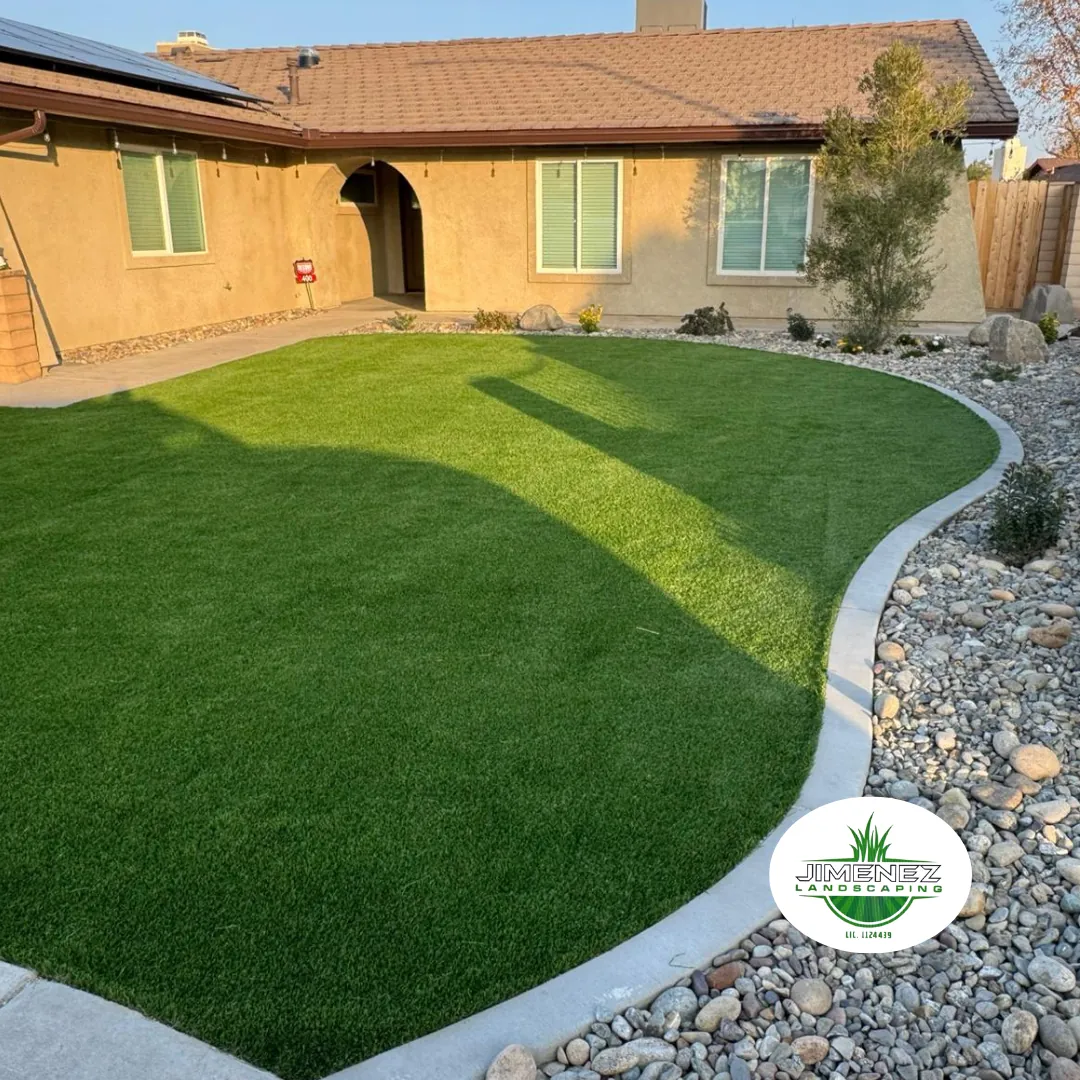 Lush artificial turf lawn installation with decorative rock border in front of a residential home, showcasing Jimenez Landscaping's expertise in Bakersfield landscaping services.