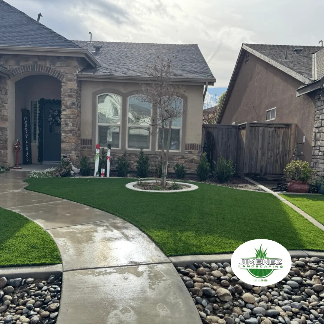 Paver walkway leading to a beautifully landscaped front yard with artificial turf, decorative rocks, and a circular flower bed, showcasing Jimenez Landscaping's hardscaping services in Bakersfield.