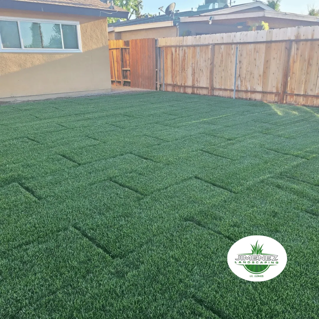 Artificial turf installation in a backyard by Jimenez Landscaping, featuring lush green grass and a fenced area, ideal for outdoor gatherings in Bakersfield.