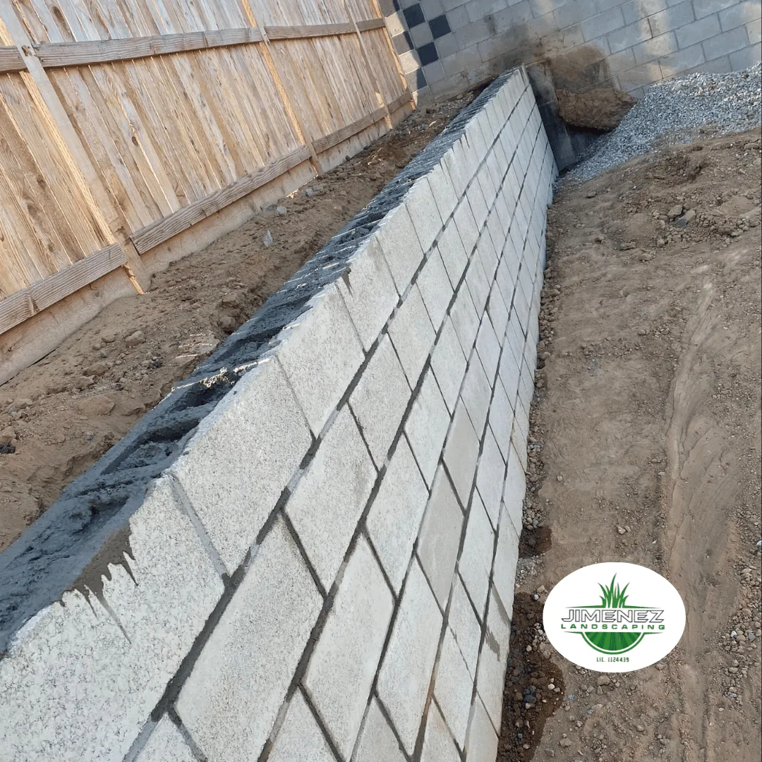 Masonry retaining wall under construction, showcasing precise stone alignment and craftsmanship by Jimenez Landscaping in Bakersfield.