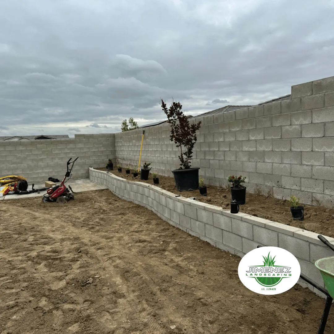 Masonry retaining wall with potted plants in a landscaped area, showcasing Jimenez Landscaping's expertise in Bakersfield masonry services.