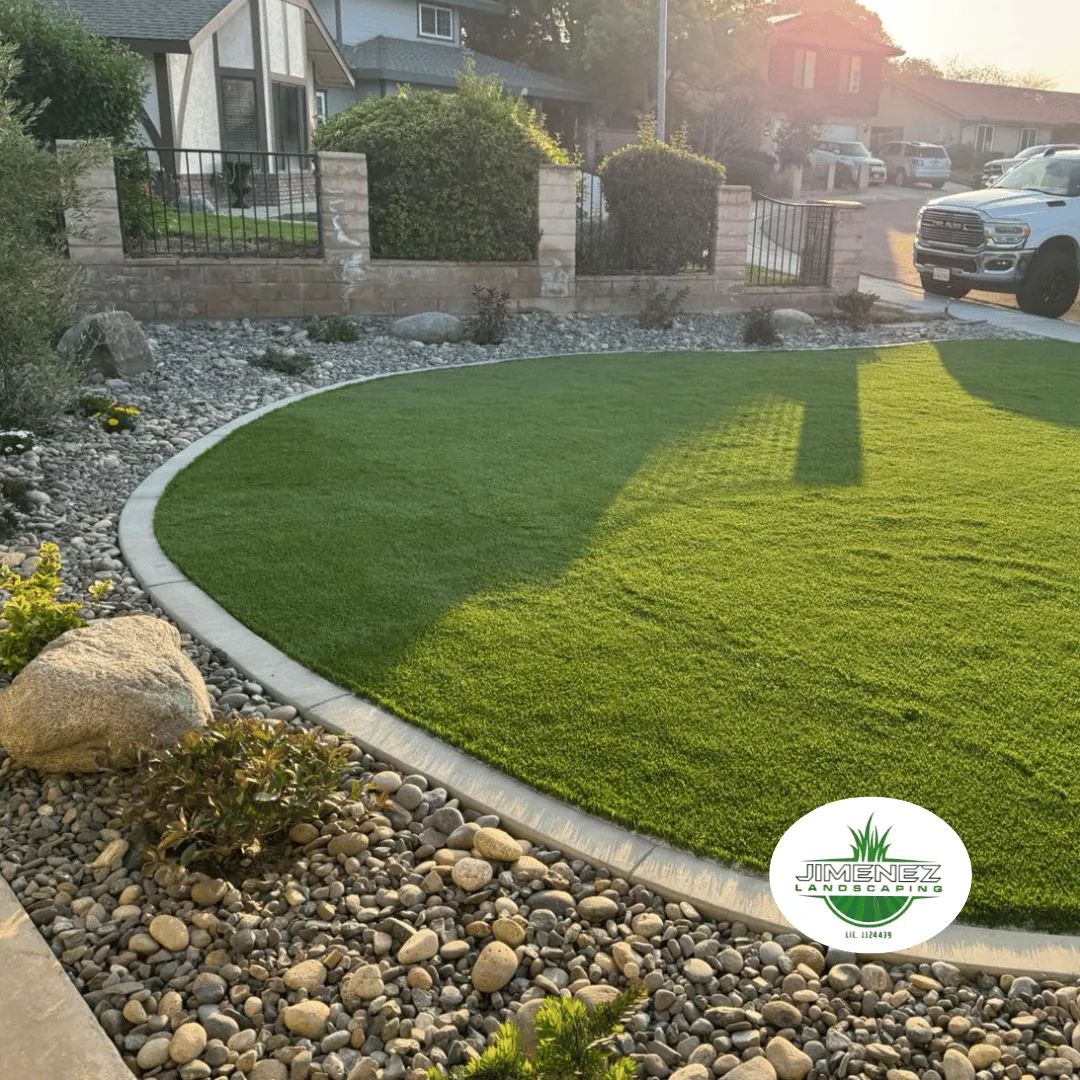 Artificial turf lawn installation with decorative rock border, showcasing a beautifully landscaped yard in Bakersfield.