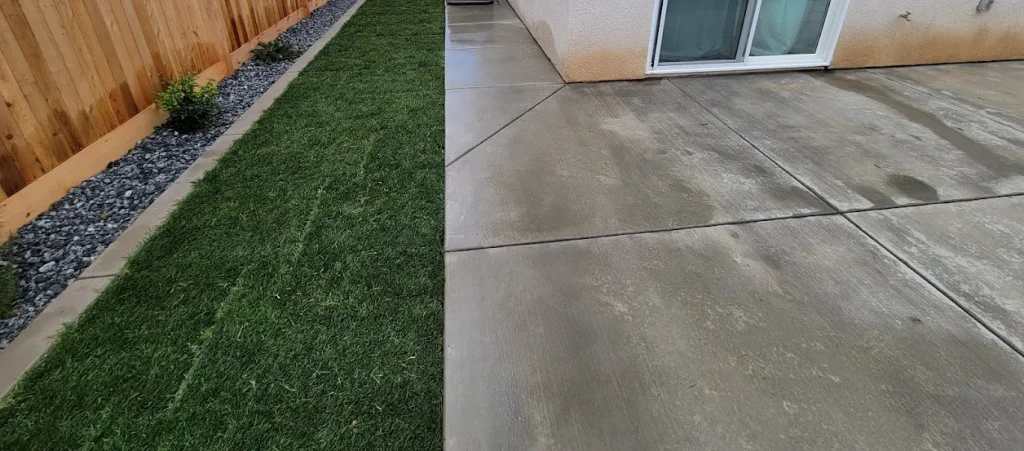 Lush artificial turf and smooth concrete patio installed by Jimenez Landscaping in Bakersfield, showcasing a well-designed outdoor space with decorative rock border.