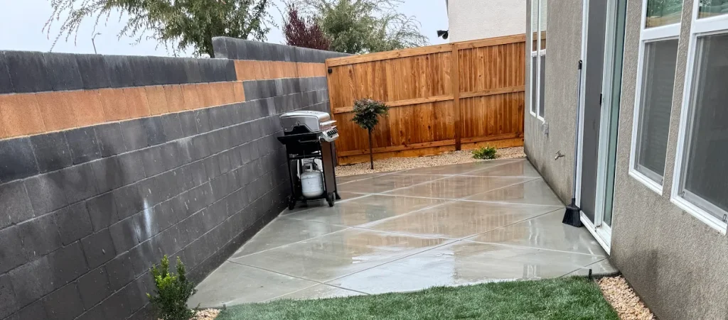 Concrete patio with decorative rock and small plants in a residential backyard in Taft, CA, showcasing Jimenez Landscaping's quality hardscaping and landscape design services.