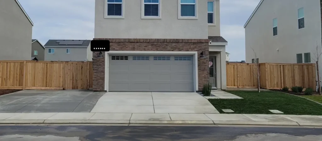 Concrete driveway and landscaped yard in Bakersfield, featuring smooth concrete work, adjacent grass area, and wooden fencing.