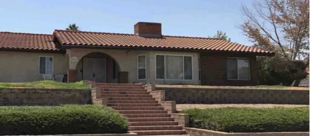 House with a terracotta tile roof, landscaped front yard featuring green shrubs and a stone retaining wall, located in Bakersfield.