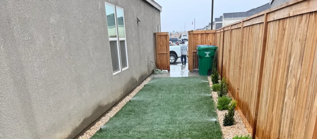 Sod installation along a narrow side yard with decorative rock and small shrubs, showcasing quality landscaping work by Jimenez Landscaping in a residential area near Bakersfield.