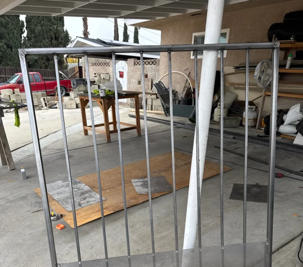 Metal gate fabrication in a landscaping workspace, showcasing tools and materials for concrete and gate installation in Bakersfield.