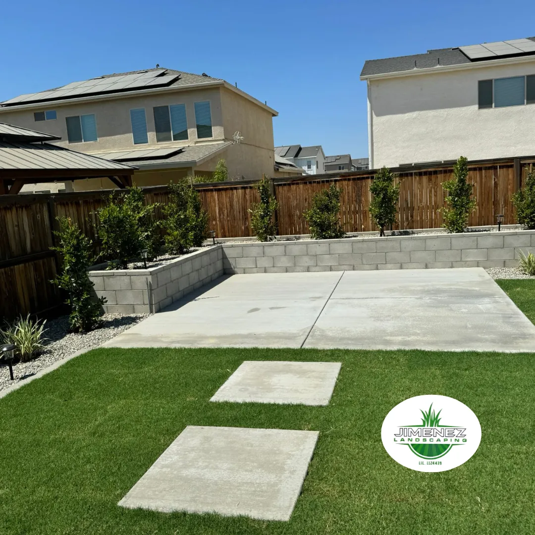 Backyard featuring freshly installed sod, concrete patio, and decorative gravel border, showcasing a well-maintained landscape by Jimenez Landscaping in Bakersfield.